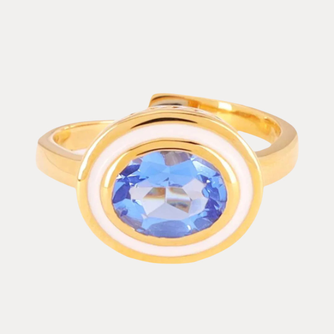 Gold ring with a blue gemstone on a light gray background