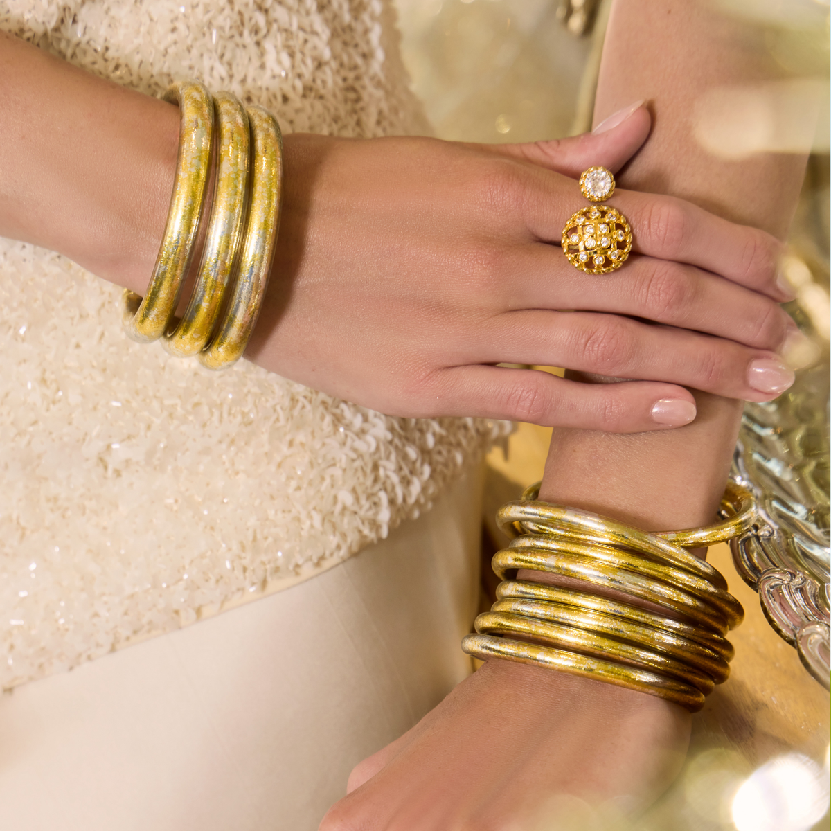 BuDhaGirl gold and silver tone bangle bracelets for women styled on two wrists with layered rounded bands and a textured gold ring