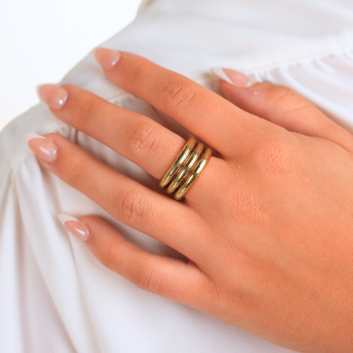 Hand wearing a gold ring on a white background