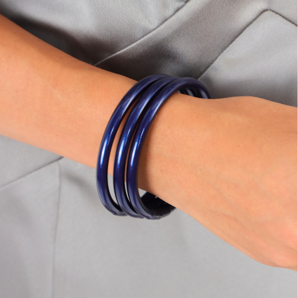 The Midnight Kelly Bundle showcasing metallic navy Bangle Bracelets worn on a wrist, celebrating timeless elegance.