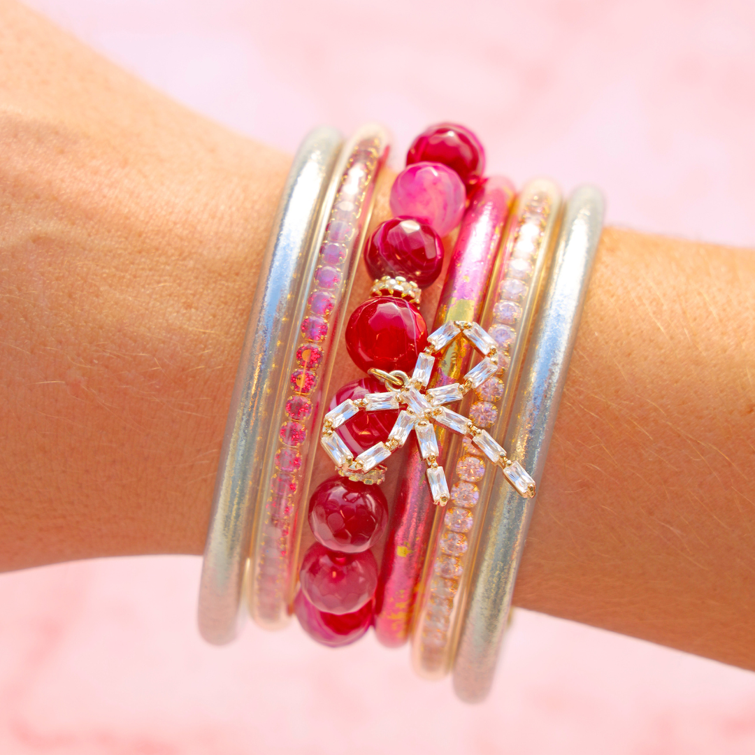 Stack of colorful bracelets on a wrist with a pink background