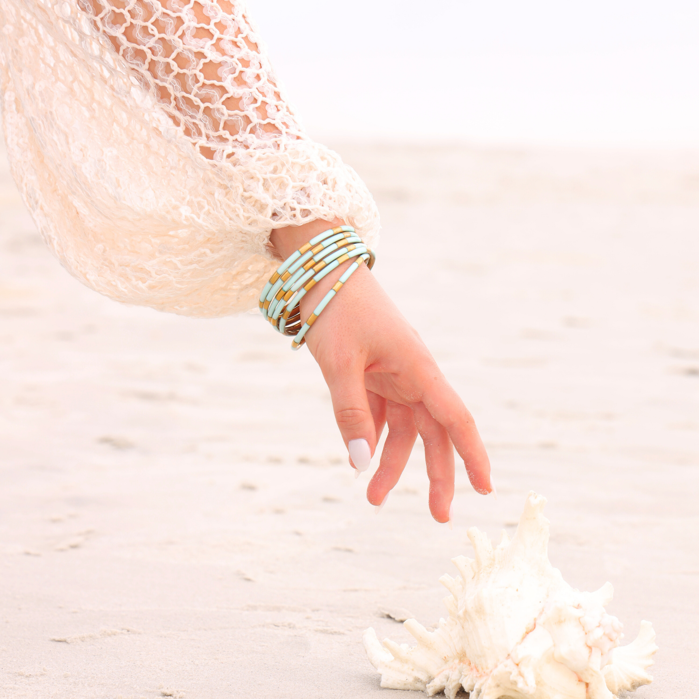 a hand reaching for a shell on sand