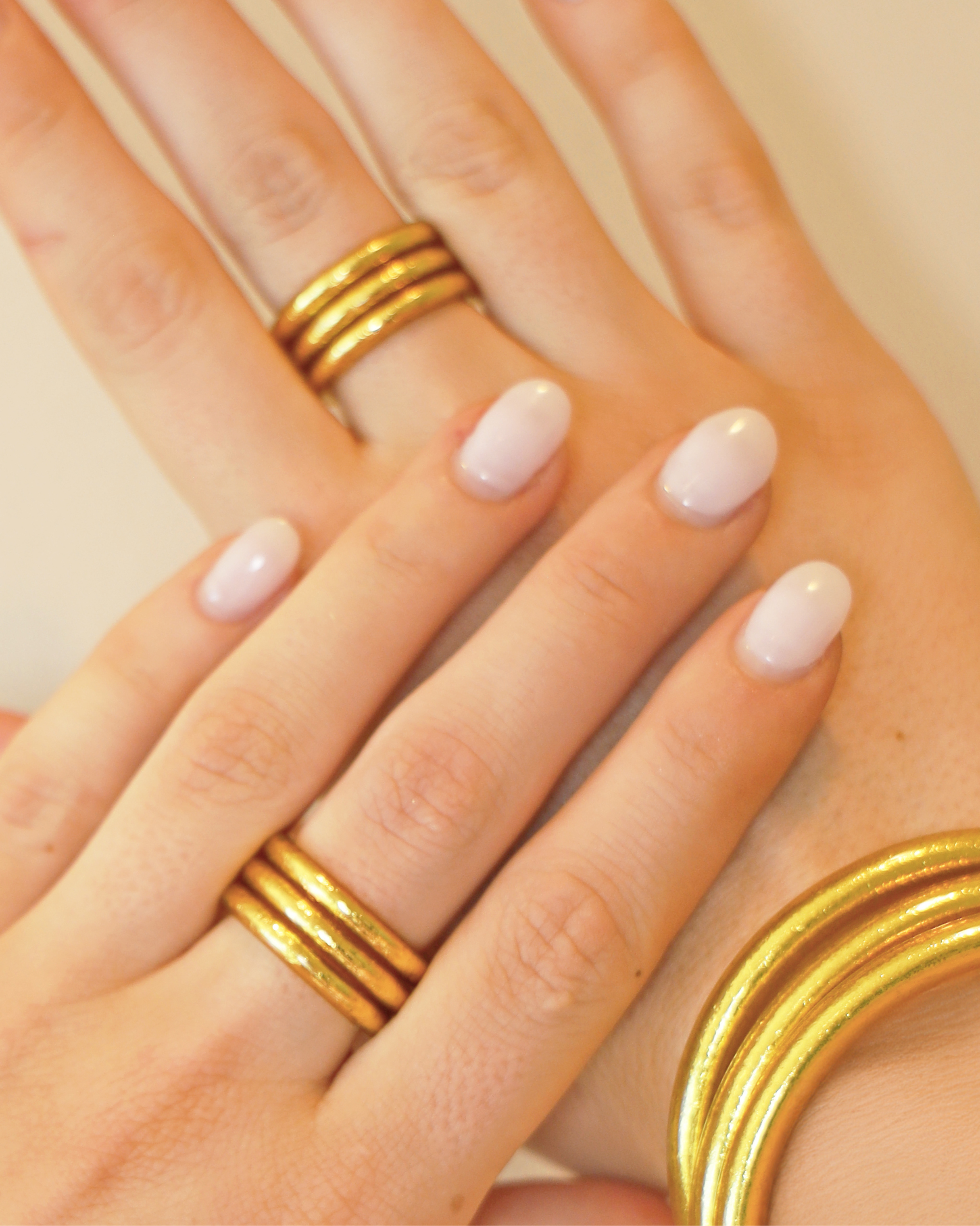a close up of a hand with gold rings