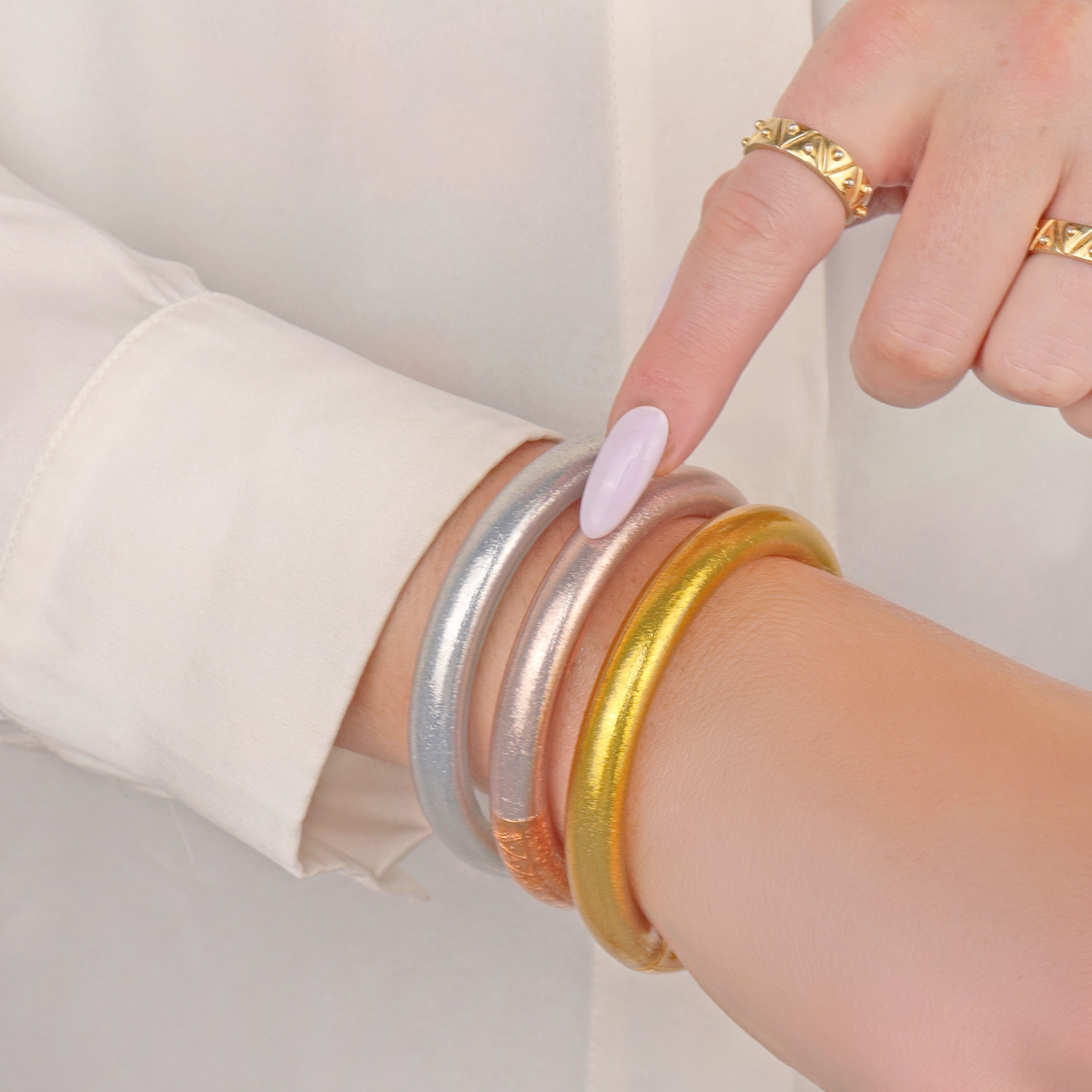 a person wearing a white shirt and gold and silver bracelets