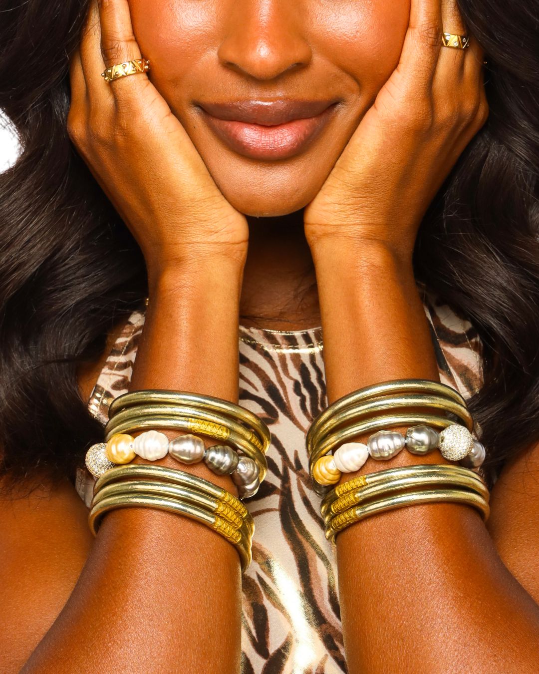 Woman in Animal Print Dress Wearing Etoile Light Gold All Weather Bangle Bracelets and Isabel Baroque Pearl Bracelets | BuDhaGirl