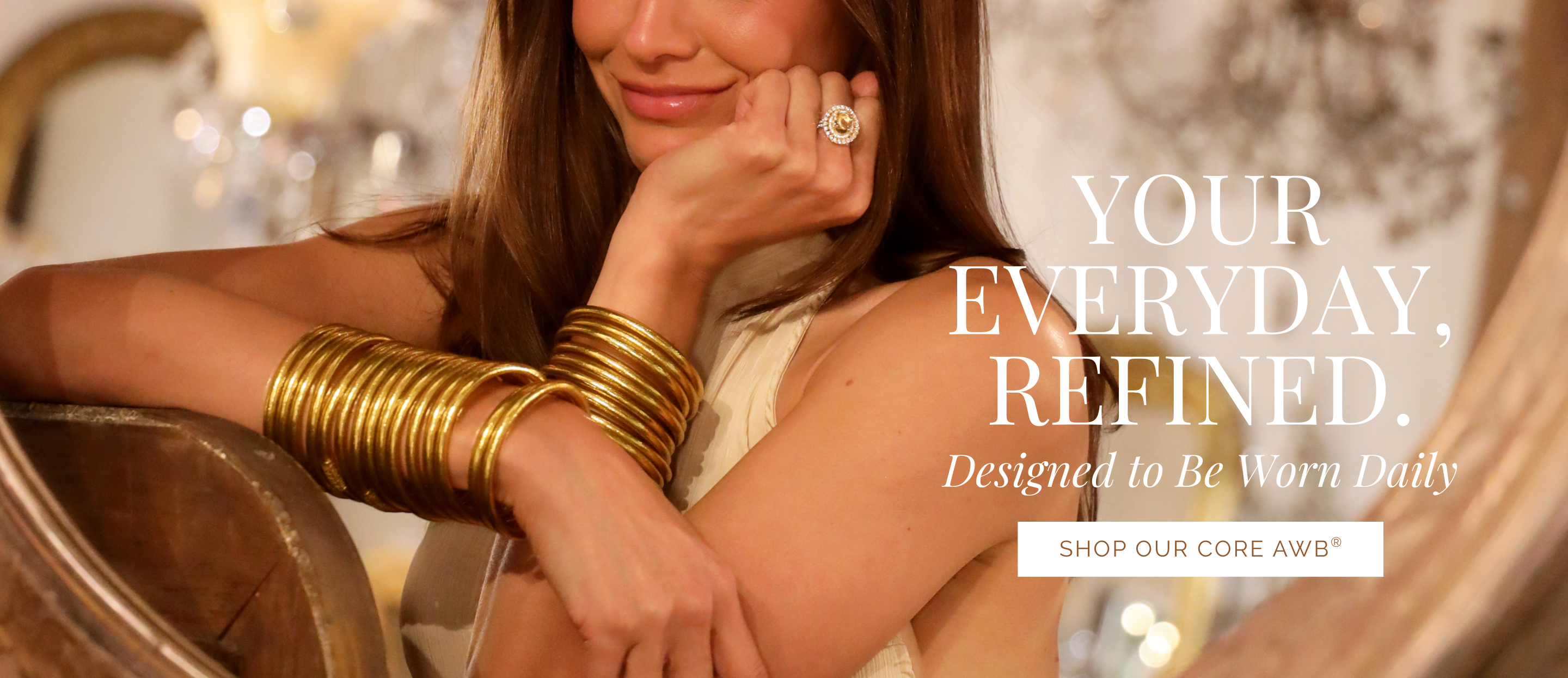 Woman wearing gold jewelry with text 'Your Everyday, Refined' on a blurred background