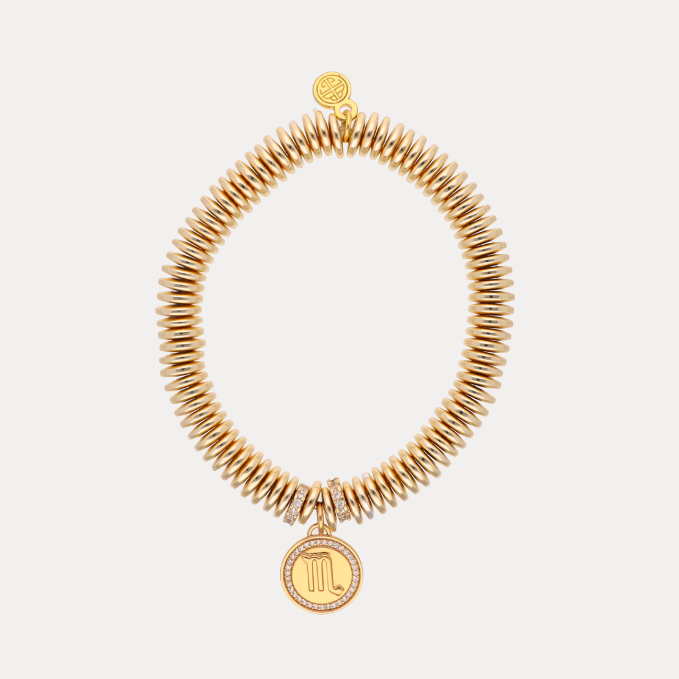 Gold coil bracelet with Scorpio symbol charm on a white background