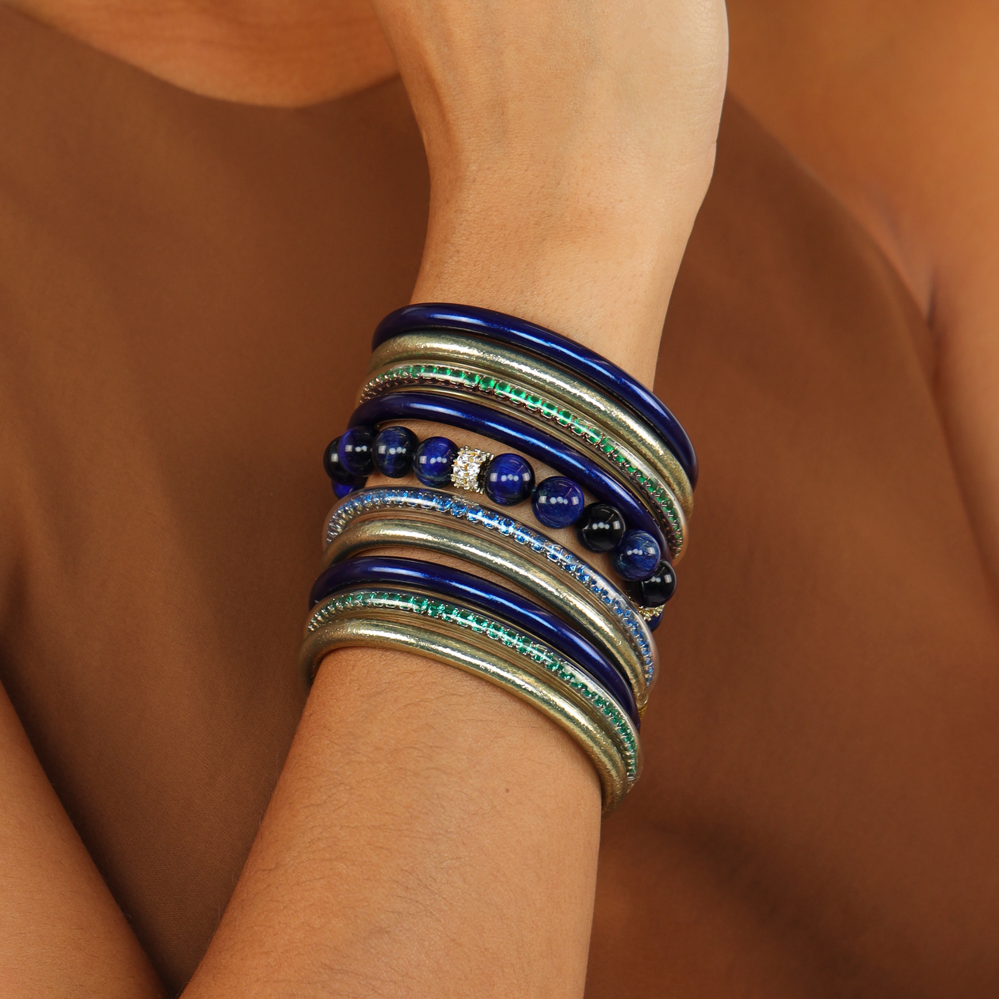 The Imperial Cosmos Bundle featuring bangle bracelets with deep blue and green tones on a wrist.